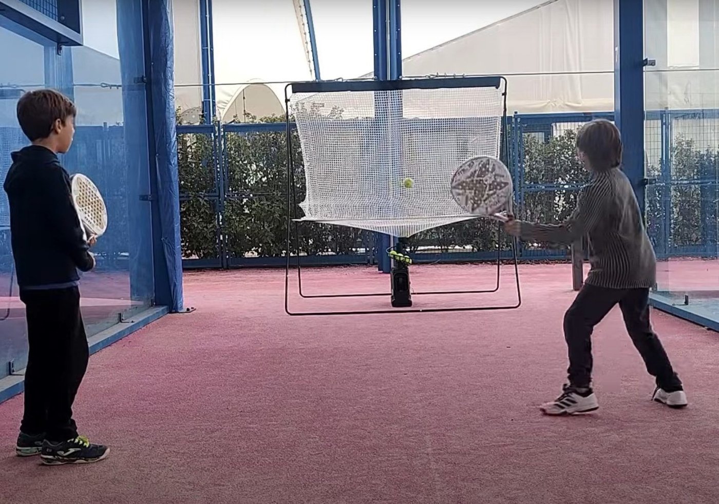 Dos niños jugando al pádel con la red de ciclo continuo de Pro Pádel GO