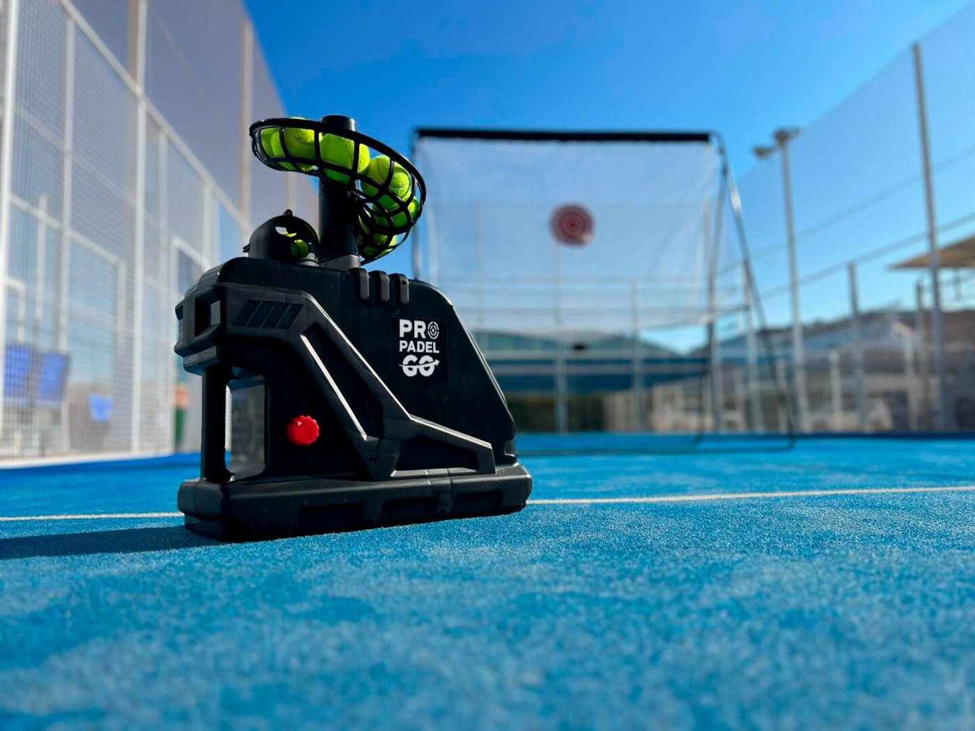 Máquina lanzapelotas Pro Pádel GO cargada de pelotas en una pista de pádel